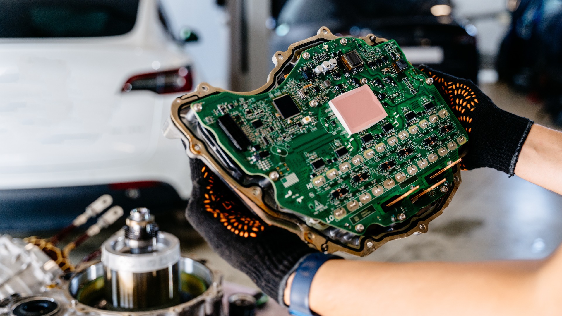 Die elektronische Steuereinheit (ECU) eines modernen Elektroautos in den Händen eines Kfz-Mechanikers oder Autoreparateurs. Motor-Wechselrichter. Wechselrichtermodul für den Hinterradantrieb