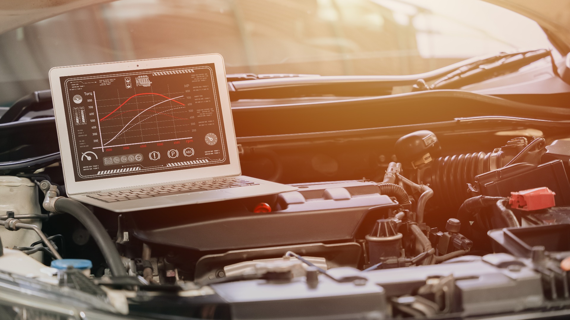 Nahaufnahme eines Laptops mit der Leistungsoptimierung des Steuergeräts eines Rennwagenmotors mithilfe moderner Software; Anzeige von Drehmoment und Leistung auf dem Bildschirm